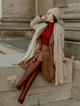 a lady wears a midi skirt with a red turtleneck top with a lapel coat